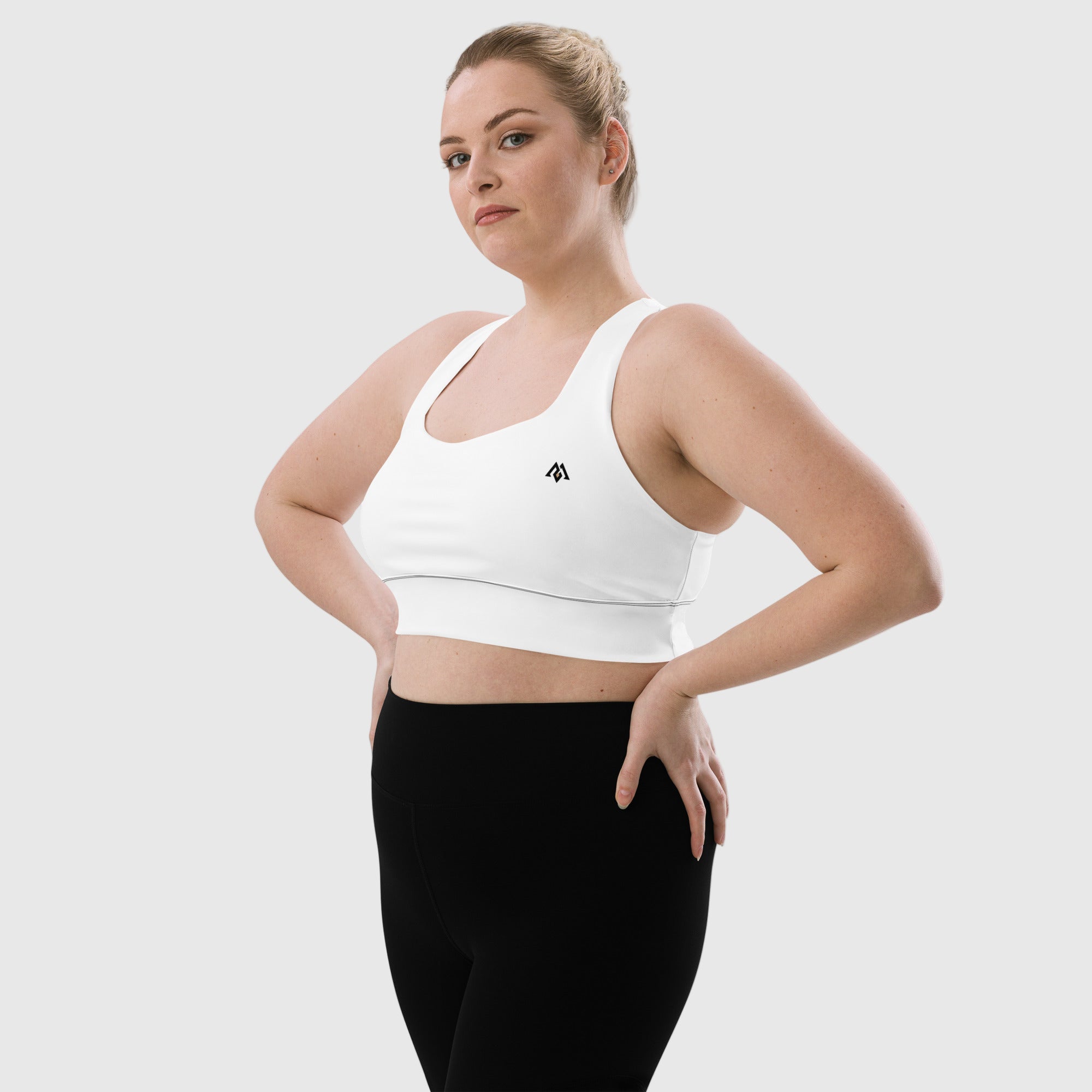 Woman wearing a white sports bra and black leggings on a white background