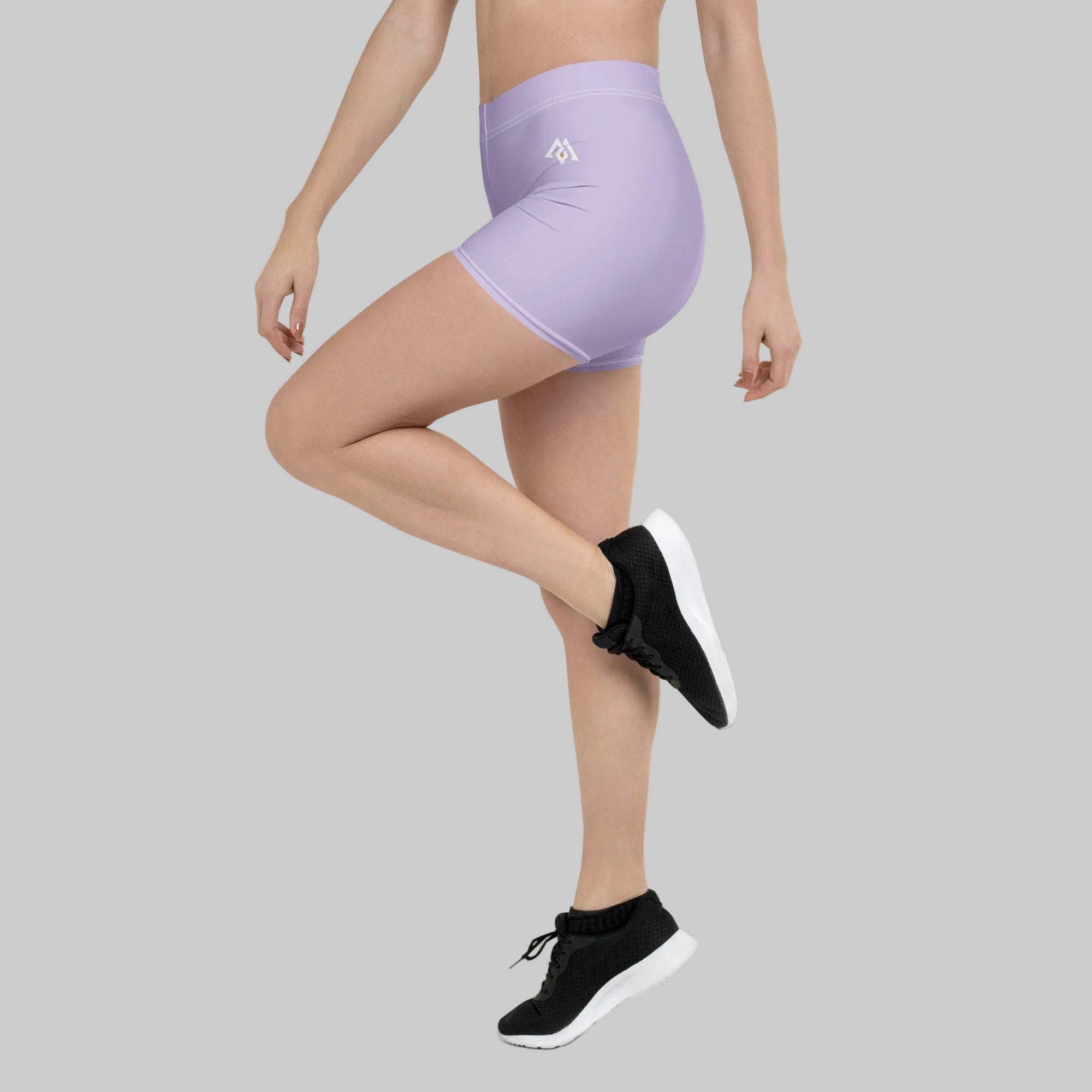 Person wearing light purple athletic shorts and black sneakers on a white background